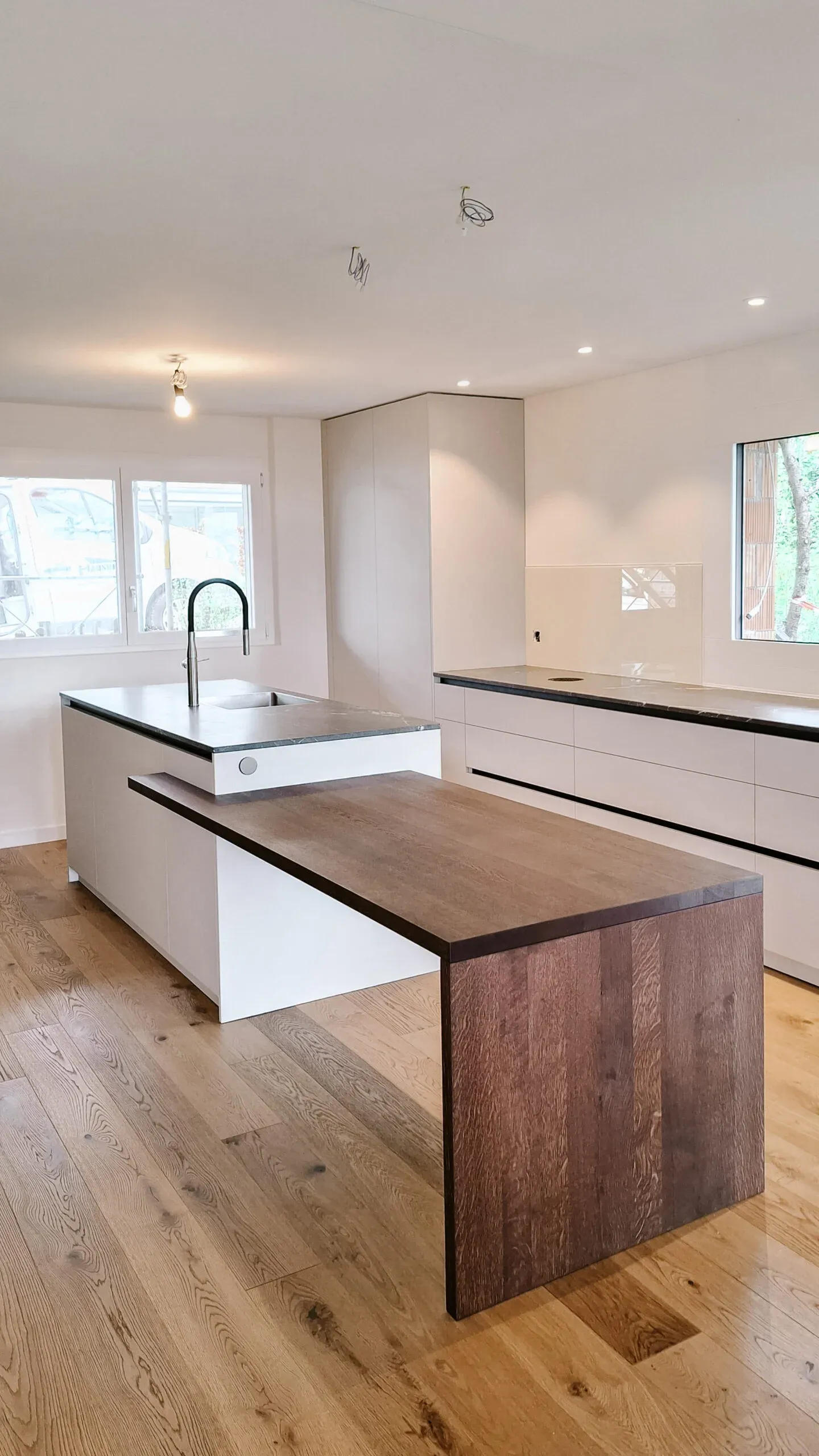 Küche mit weisser Kochinsel und angesetztem Esstisch aus dunklem Holz